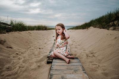 Young girl sitting on private board walk going out to lake