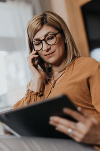 Businesswoman talking on phone while using digital tablet