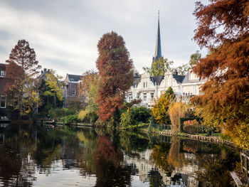 Trees and buildings by lake against sky