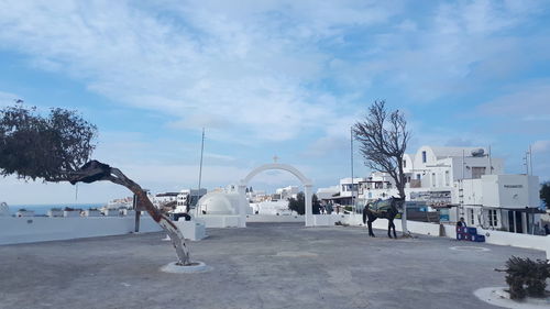 Bare trees on snow covered city against sky