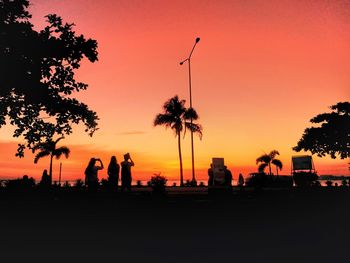 Silhouette of men on tower against sky during sunset