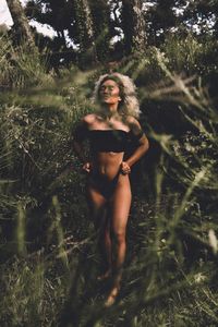 Full length of woman in lingerie standing amidst plants