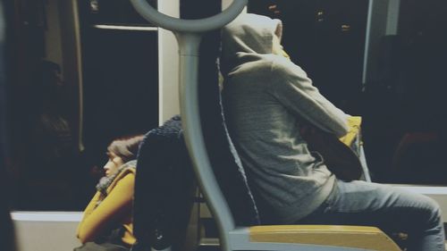 Side view of couple sitting on chair at store