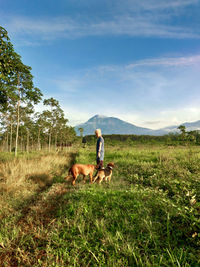 Woman standing with dog on field against sky