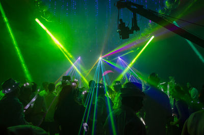 Green light beams falling on people in nightclub