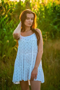 Young beautiful woman in white dress in corn field.
