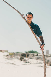 Young man standing on beach against clear sky
