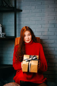 Portrait of beautiful young woman standing against brick wall