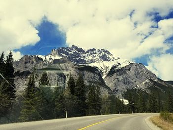 Road by mountains against sky