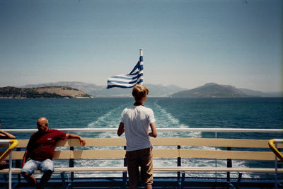 Rear view of men looking at sea against sky