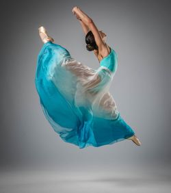 Low section of woman with arms raised against blue background