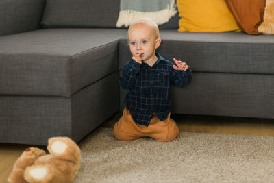 Low section of boy sitting on sofa at home