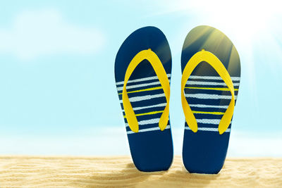 Close-up of yellow shoes on beach against sky