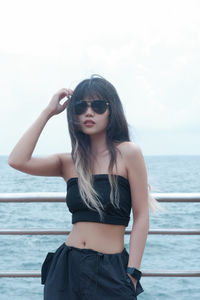 Portrait of young woman standing against sea