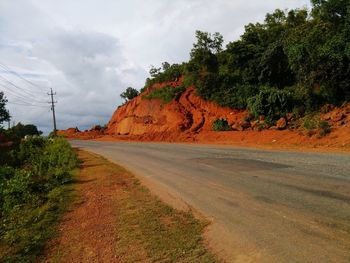 Road by trees against sky