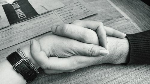 High angle view of man and woman holding hands at table