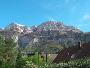 Houses by mountains against blue sky