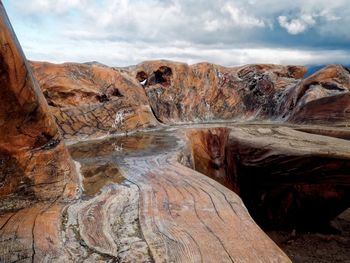 Rock formations on beach against cloudy sky