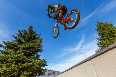 Low angle view of man performing bicycle stunt against sky