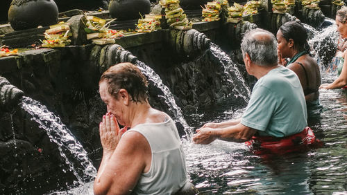 Friends splashing water at waterfall