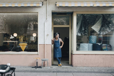 Full length of male upholstery worker looking away while standing at workshop entrance