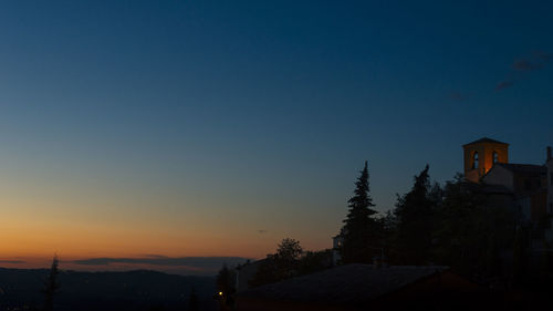 Houses and trees against clear sky during sunset