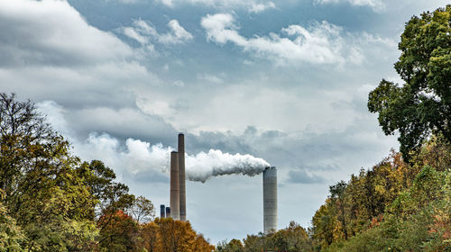 Smoke emitting from factory against sky