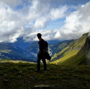 Rear view of woman standing on mountain against cloudy sky