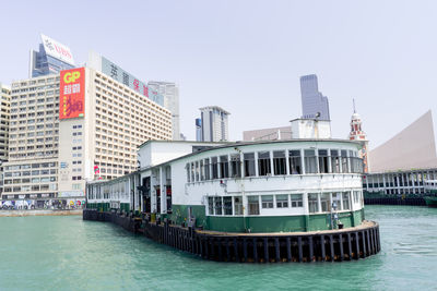 Boat in river by buildings against clear sky