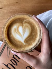 Cropped hand holding coffee on table