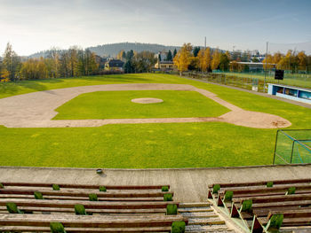 Youth baseball field viewed from behind home net in morning light.