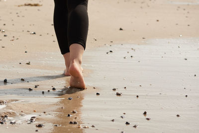 Low section of woman walking on sand