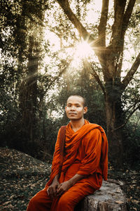 Portrait of smiling young man sitting on tree