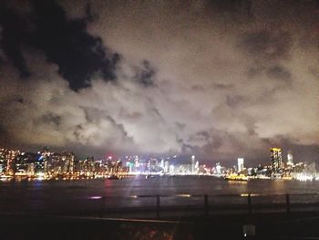 View of illuminated cityscape against cloudy sky
