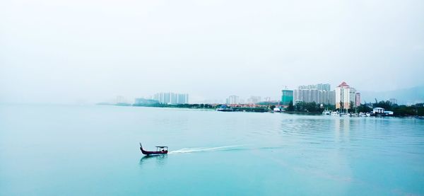 Scenic view of sea and buildings against clear sky