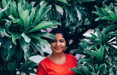 Portrait of smiling woman standing amidst leaves