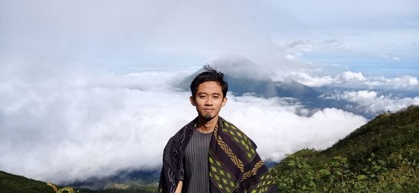 Portrait of young man standing against mountains