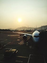 Airplane on runway against sky during sunset