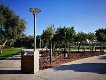 Empty street in park against clear blue sky