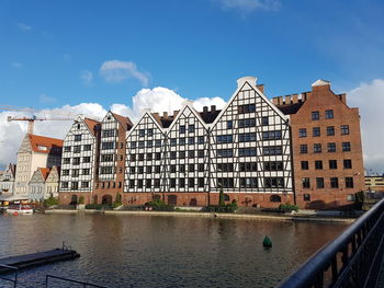 Buildings by river against sky in city