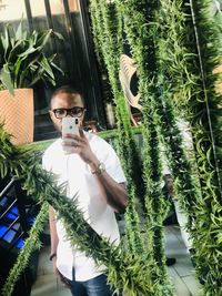 Portrait of young man standing by plants