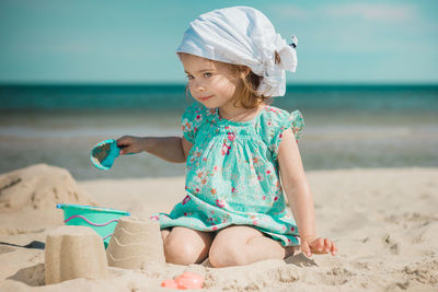 Full length of girl making sandcastles while sitting on beach