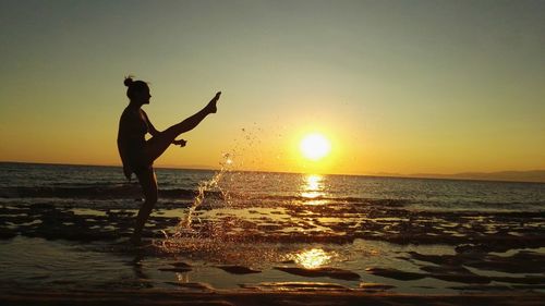 Silhouette man standing at beach during sunset