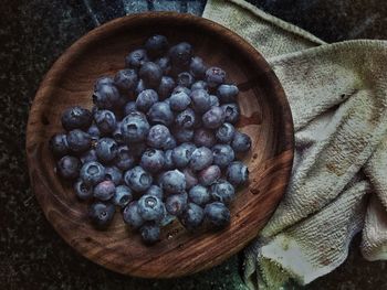 High angle view of blueberries in wooden plate on table