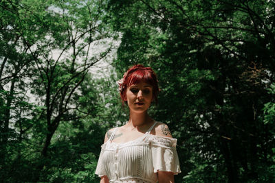 Portrait of woman standing against trees