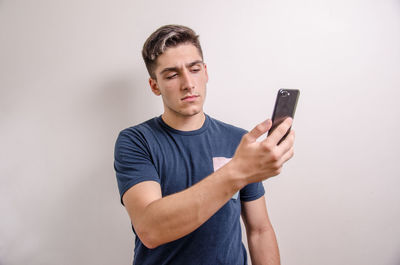 Young man using mobile phone against white background