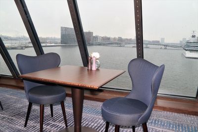 Chairs and table by glass window in city