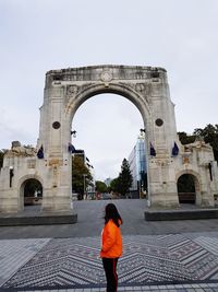 Woman standing against historic entrance in city