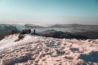 People on snowcapped mountain against sky