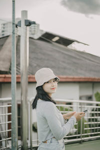 Side view of young woman standing against built structure